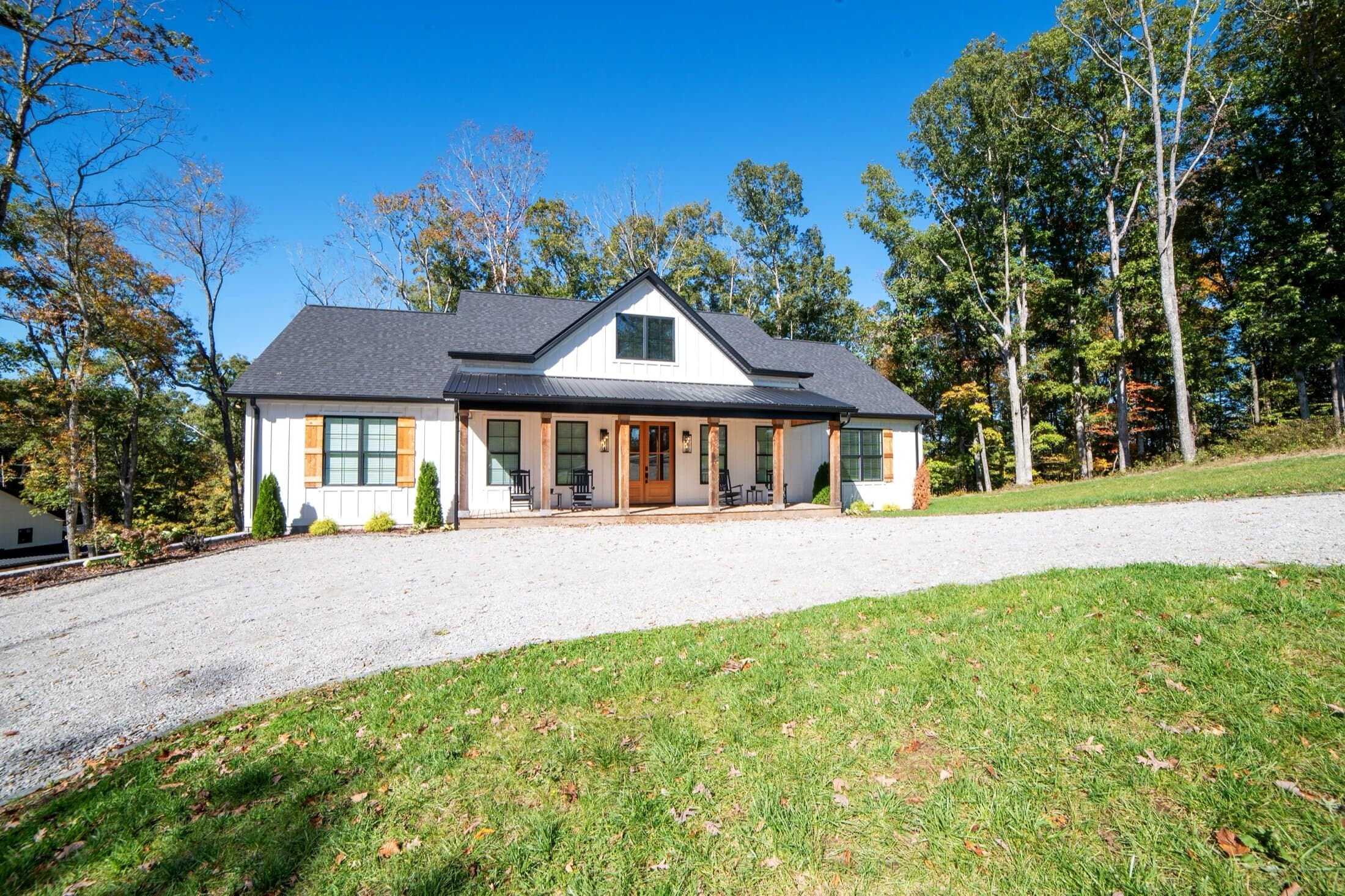 Stay at Nolin lakehouse — front exterior at golden hour, modern farmhouse with covered porch and rocking chairs in Paradise Grove on Nolin Lake